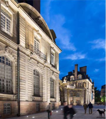 Visitantes contemplan la iluminación arquitectónica delante de un edificio de la Gran Isla de Estrasburgo iluminado por Philips Lighting