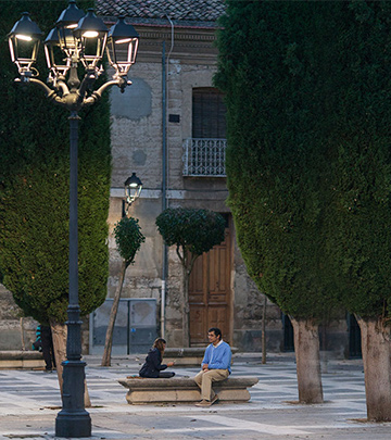 Un hombre y un niño jugando a las cartas en una calle de Palencia alumbrada con iluminación Philips